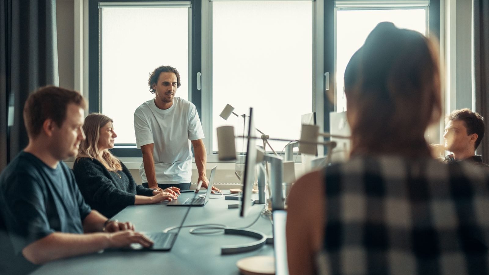 A diverse professional team engaged in discussion during a collaborative meeting in a modern office.