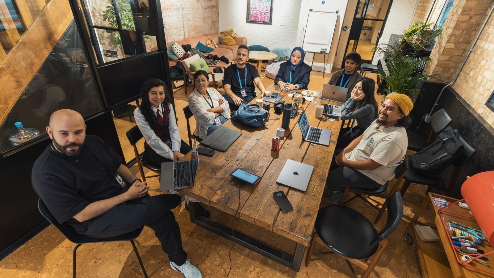 A friendly, diverse team collaborating together with laptops in a modern workspace.