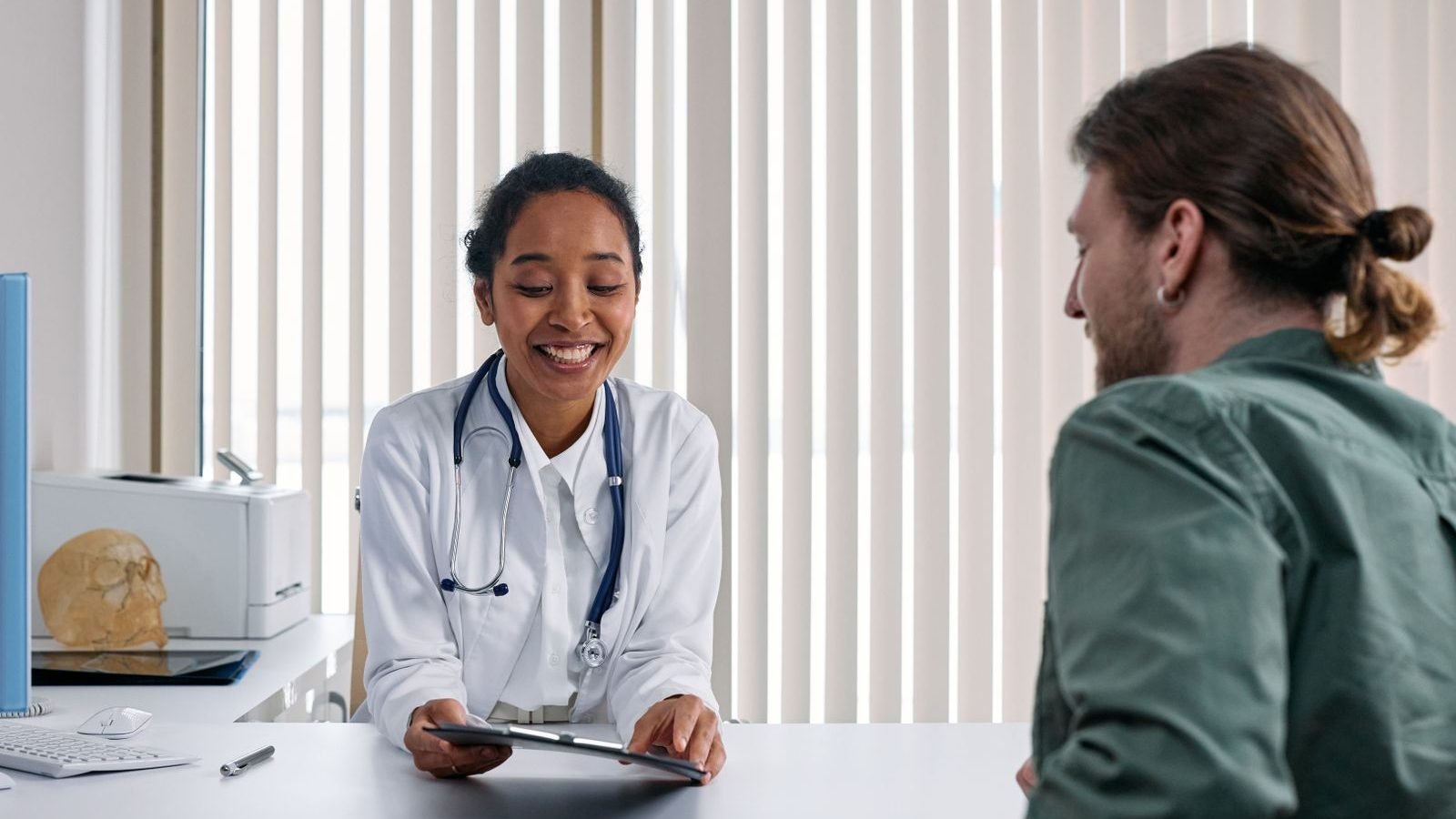 An occupational health adviser talking warmly with a person during a consultation in a bright, modern clinic.