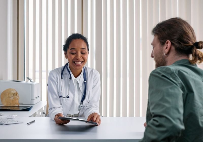 An occupational health adviser talking warmly with a person during a consultation in a bright, modern clinic.