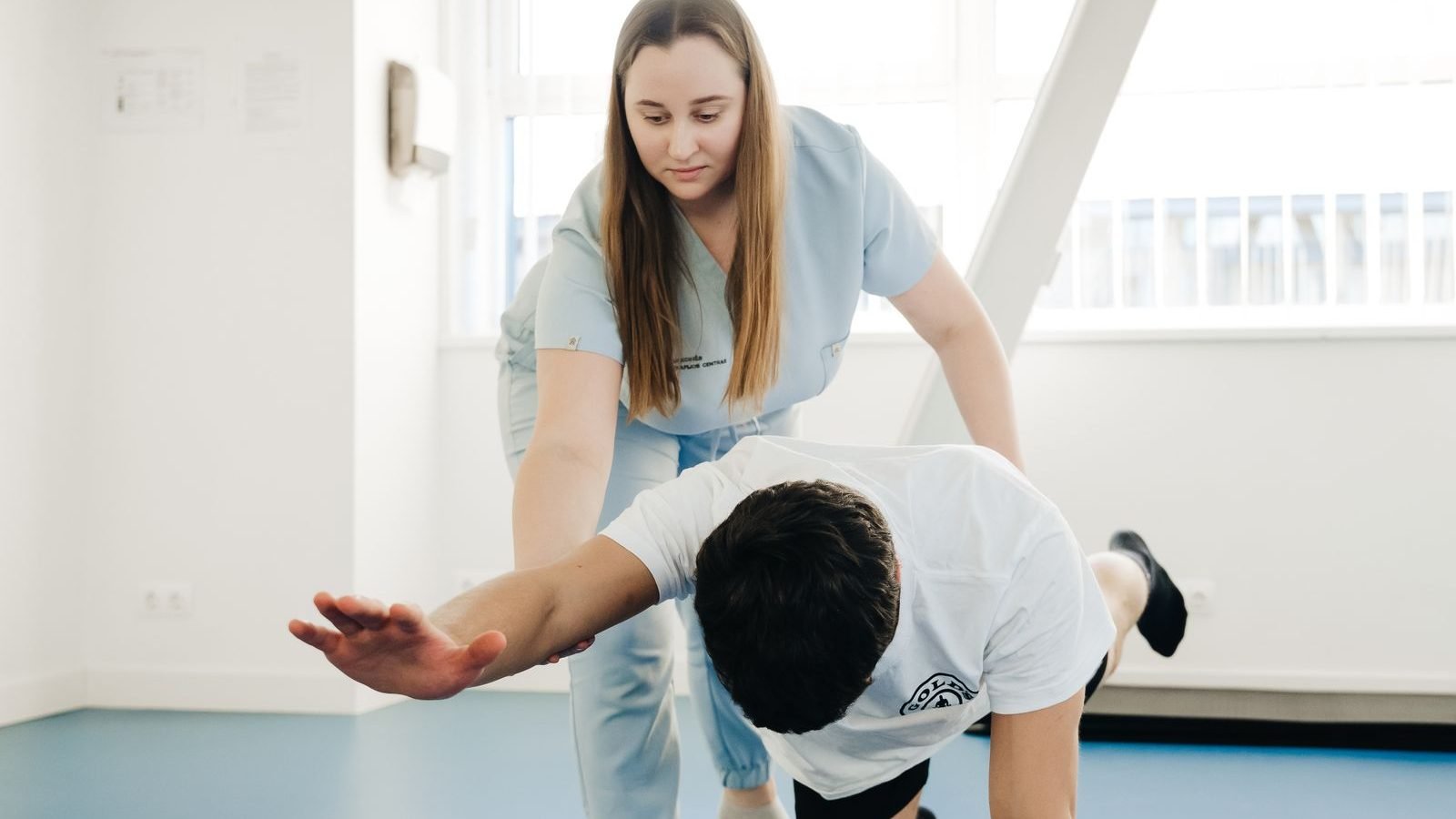 A physiotherapist guiding a person through gentle stretching exercises during a one-to-one session.