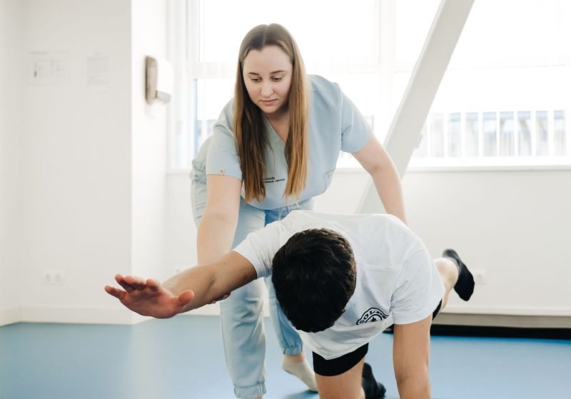 A physiotherapist guiding a person through gentle stretching exercises during a one-to-one session.