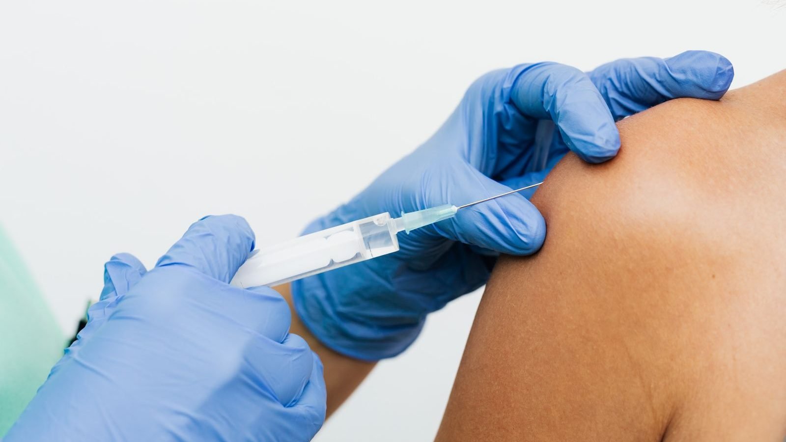 A nurse administering a vaccination into a person's upper arm at a workplace clinic.