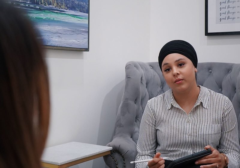Two people in a calm, supportive one-to-one wellbeing conversation, seated across from each other.