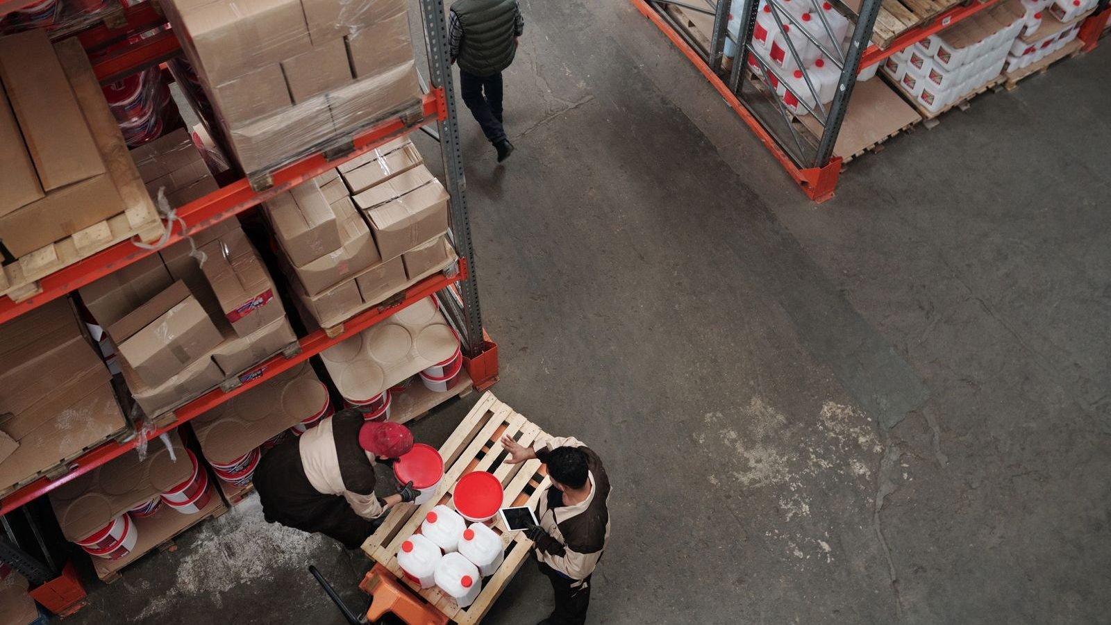 Warehouse workers handling inventory and boxes among shelving in a busy distribution centre.