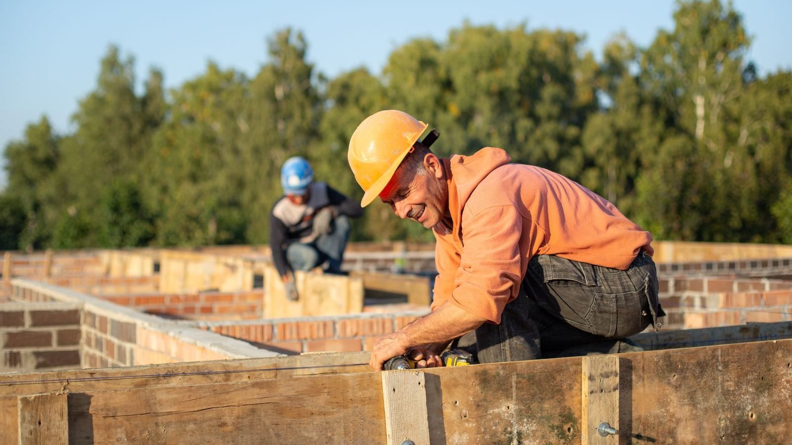 Construction workers in hard hats working outdoors on a building site in daylight