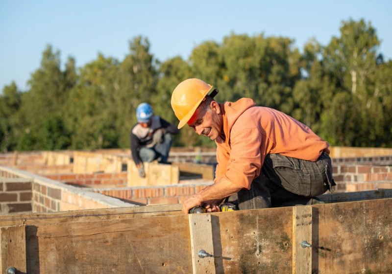 Construction workers in hard hats working outdoors on a building site in daylight