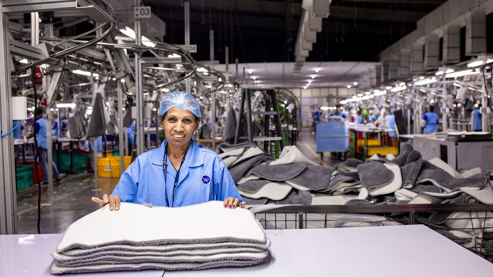 Worker on a manufacturing production line handling products among industrial machinery