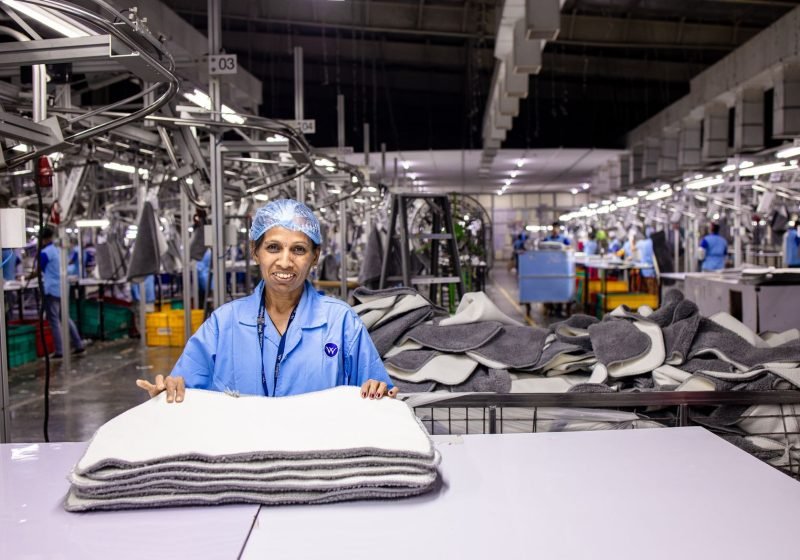 Worker on a manufacturing production line handling products among industrial machinery